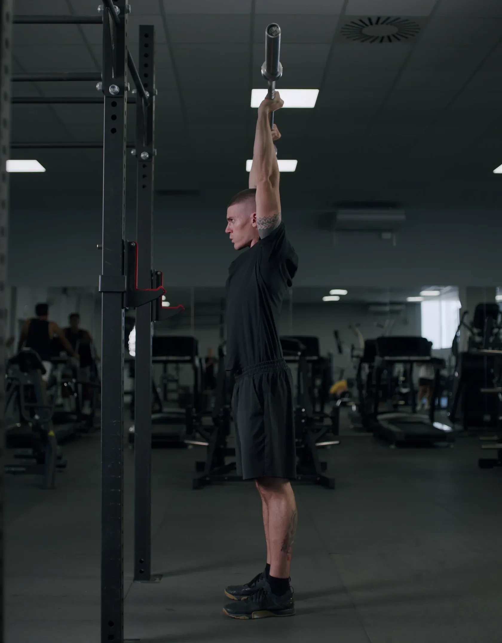 Athlete pressing a barbell overhead in a Mentor partner gym