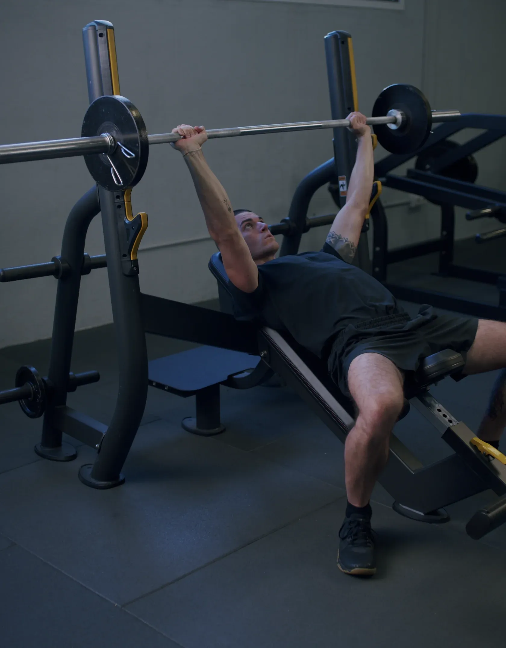 Athlete pressing a barbell on an incline bench in a Mentor partner gym
